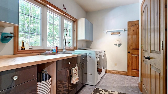 laundry room with washer and clothes dryer, light tile patterned floors, cabinet space, a sink, and baseboards