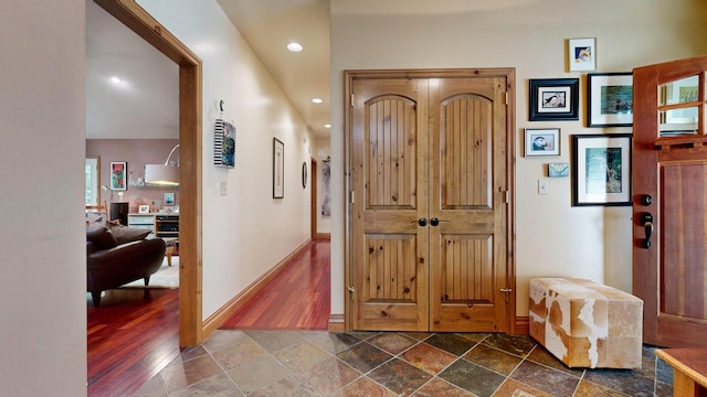 hallway with baseboards, recessed lighting, and stone tile floors