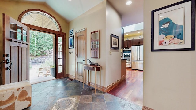 foyer entrance with lofted ceiling, stone tile floors, baseboards, and recessed lighting