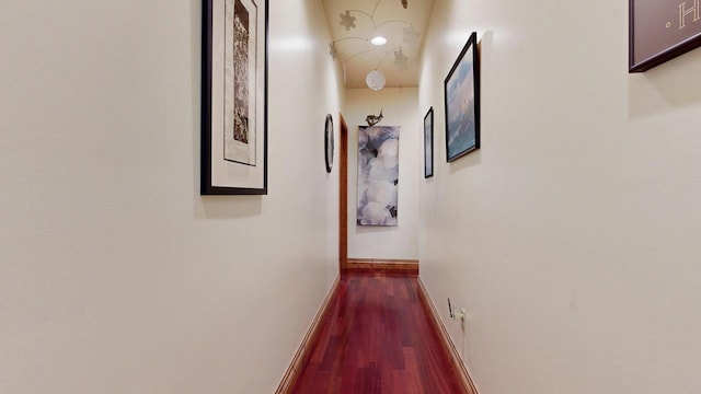 hallway featuring baseboards and dark wood-type flooring