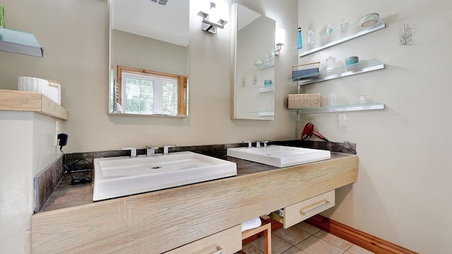 full bathroom featuring double vanity, tile patterned flooring, a sink, and baseboards