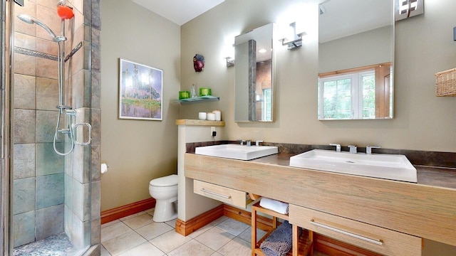 bathroom with a stall shower, a sink, baseboards, and tile patterned floors