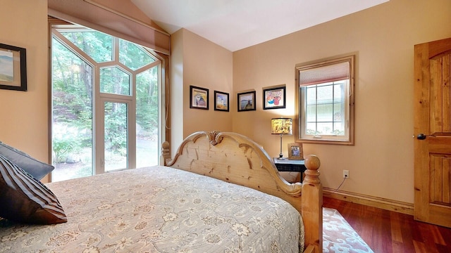 bedroom featuring lofted ceiling, baseboards, and dark wood-style flooring