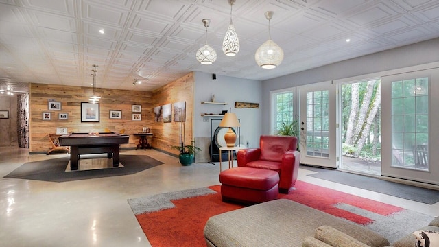 playroom featuring pool table, an ornate ceiling, finished concrete floors, and wooden walls