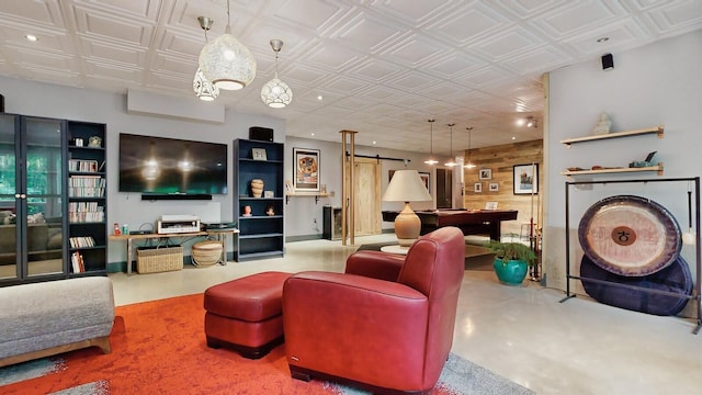 living room featuring finished concrete flooring, a barn door, wooden walls, and an ornate ceiling