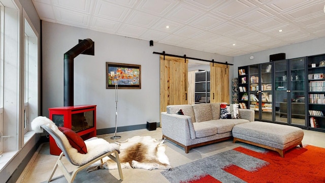 living room featuring an ornate ceiling, recessed lighting, a barn door, a wood stove, and baseboards