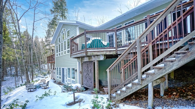 snow covered back of property with stairway