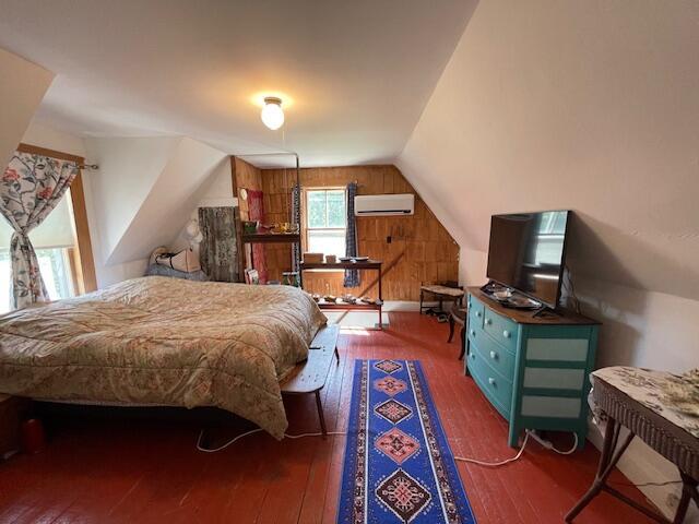 11 Sardine Way, Lubec, ME 04652 - bedroom featuring wood-type flooring, a wall mounted air conditioner, wooden walls, and vaulted ceiling