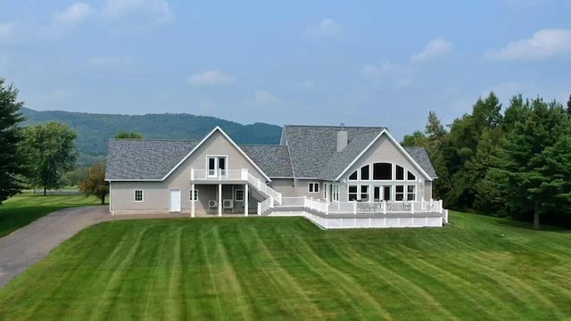 back of house with stairs, a chimney, a wooden deck, and a yard