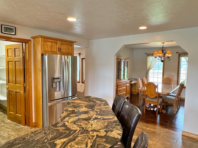 kitchen featuring arched walkways, recessed lighting, a textured ceiling, a chandelier, and stainless steel fridge