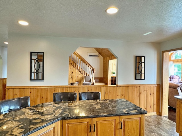 bar with arched walkways, a wainscoted wall, stairs, an AC wall unit, and wood walls