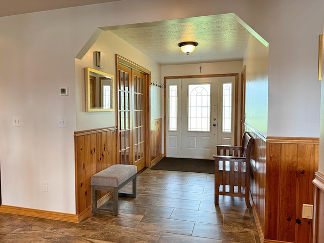 foyer entrance with a textured ceiling and wainscoting