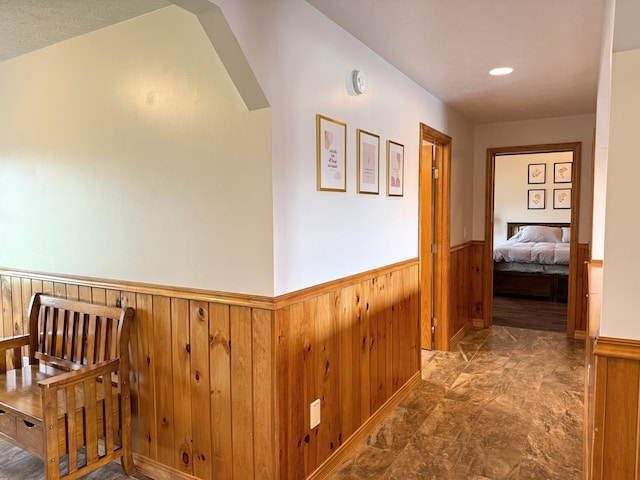 hall featuring a wainscoted wall and wooden walls