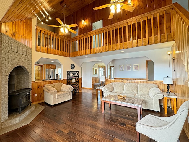 living area featuring lofted ceiling, a wood stove, wooden walls, and hardwood / wood-style flooring