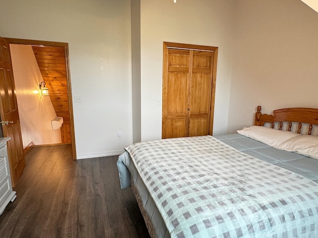 bedroom featuring dark wood-type flooring, a closet, and baseboards