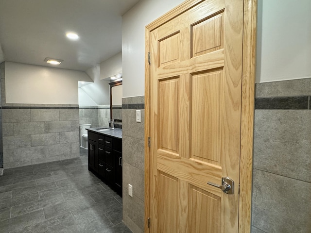 kitchen featuring a wainscoted wall, a sink, and tile walls