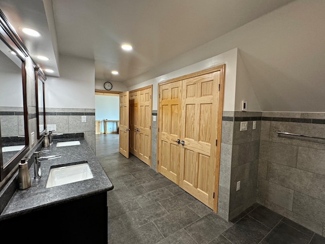 bathroom with wainscoting, a sink, and tile walls