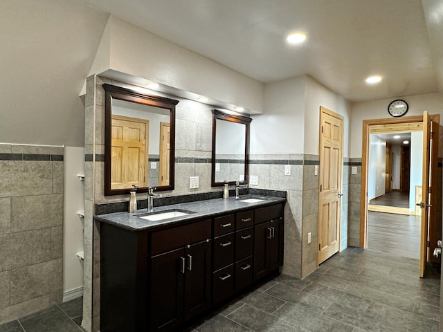 bathroom with wainscoting, a sink, tile walls, and double vanity