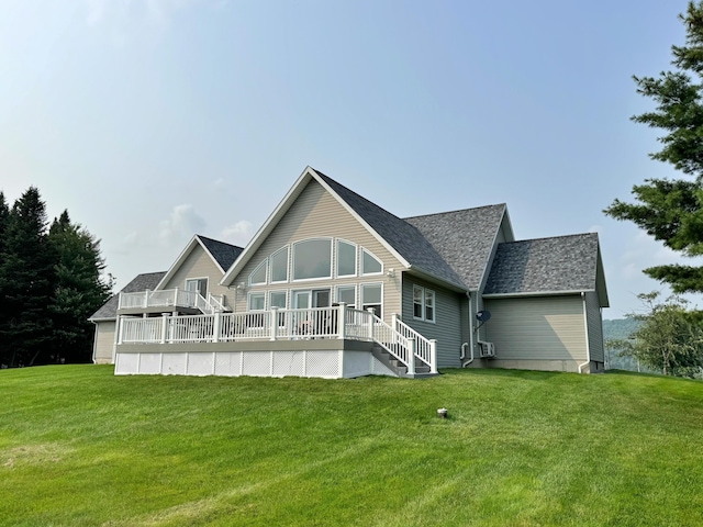 back of property with a shingled roof, a deck, and a yard