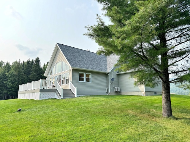 rear view of property featuring a shingled roof, a lawn, and a wooden deck