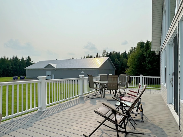 wooden terrace with outdoor dining space and a lawn