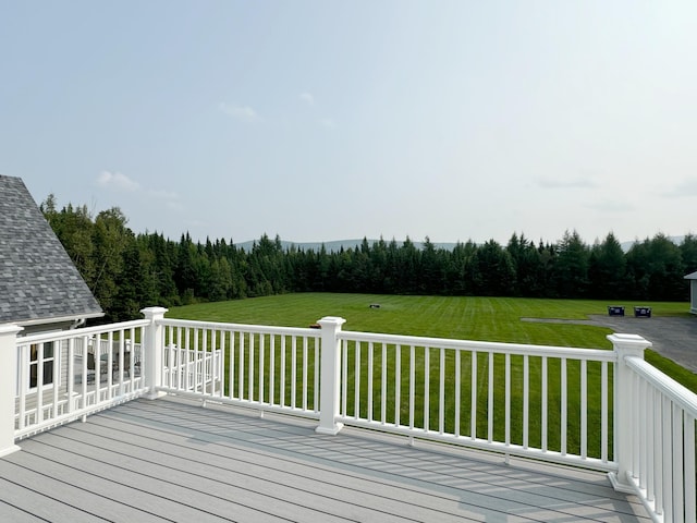 wooden terrace featuring a lawn and a view of trees