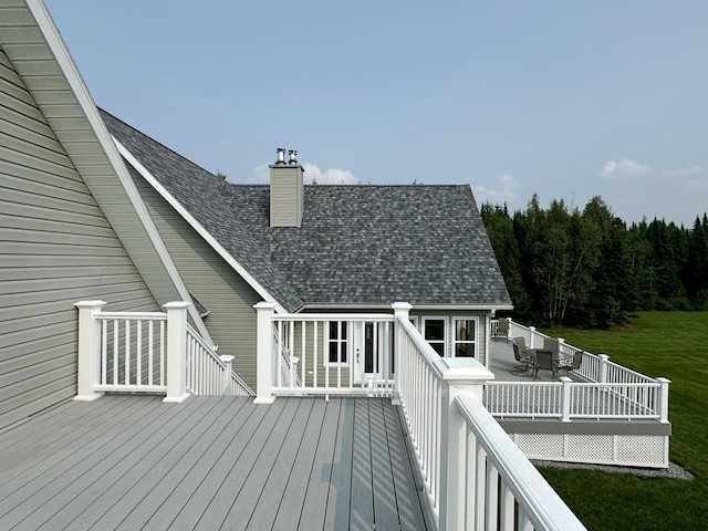 deck featuring outdoor dining space and a lawn