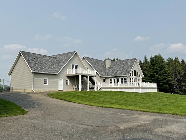 view of front facade featuring a chimney, stairway, roof with shingles, a deck, and a front lawn