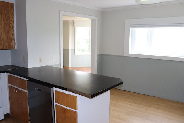 kitchen with ornamental molding, kitchen peninsula, wooden walls, black dishwasher, and light wood-type flooring