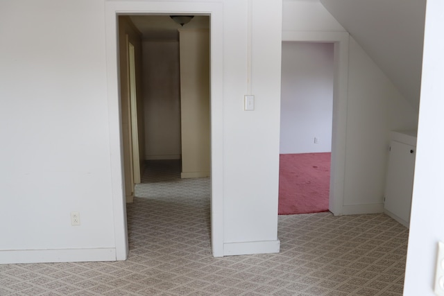 hallway with light carpet and vaulted ceiling