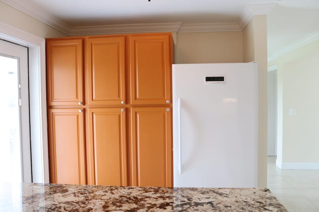 kitchen featuring ornamental molding, light stone counters, light tile patterned floors, and white fridge