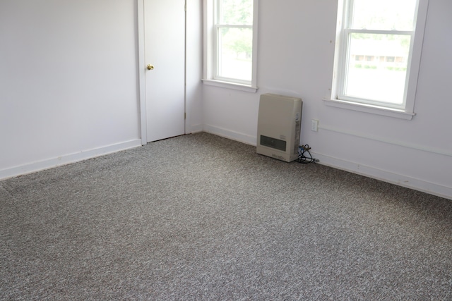 spare room with a healthy amount of sunlight, carpet flooring, and heating unit