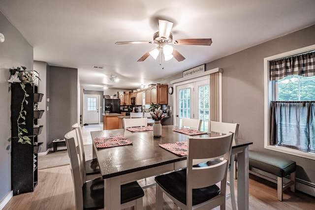 dining space with ceiling fan, light hardwood / wood-style floors, and french doors