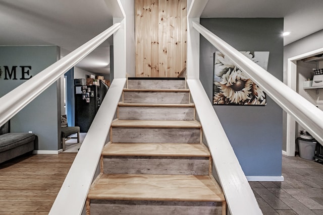 stairs with hardwood / wood-style flooring and wooden walls