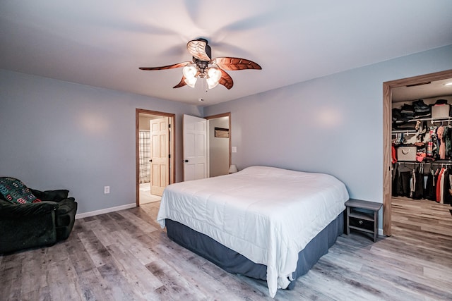 bedroom featuring ceiling fan, a spacious closet, wood-type flooring, and a closet