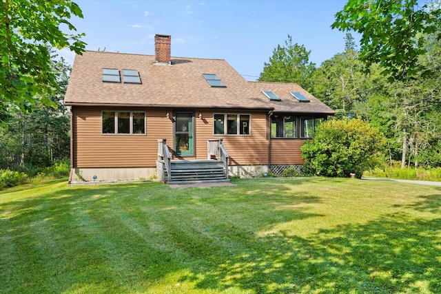 rear view of house with roof with shingles, a chimney, and a yard