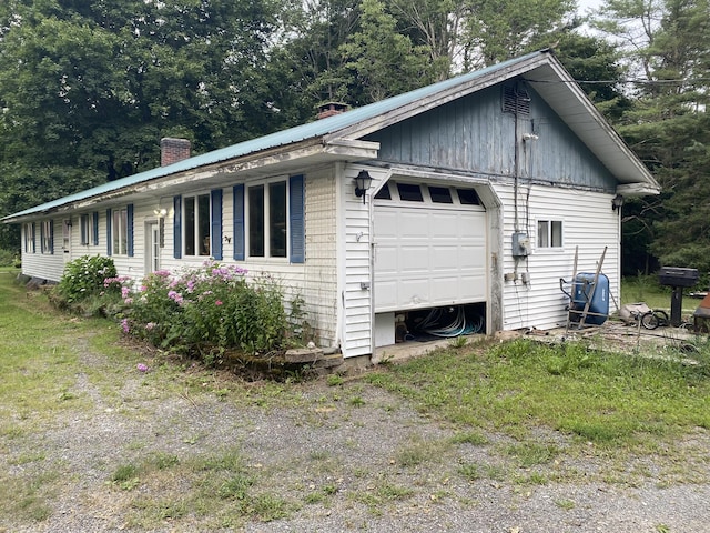 view of home's exterior featuring metal roof, dirt driveway, and a chimney