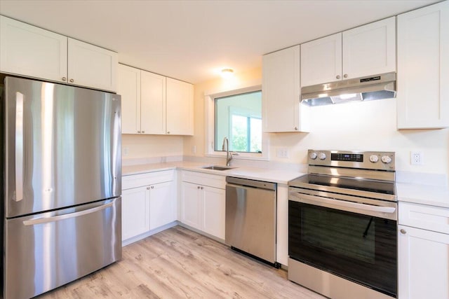 kitchen with appliances with stainless steel finishes, light hardwood / wood-style floors, white cabinetry, and sink