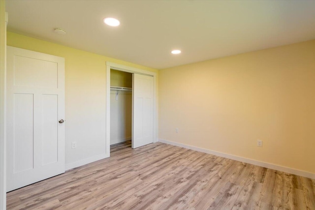 unfurnished bedroom with a closet and light hardwood / wood-style floors