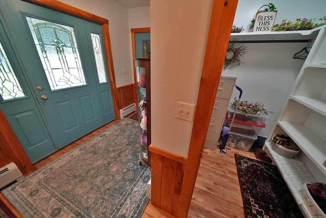 foyer featuring light wood-type flooring, wooden walls, and baseboard heating