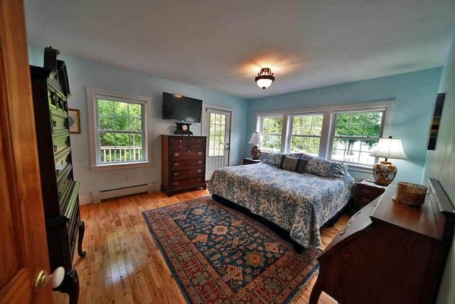 bedroom featuring multiple windows, a baseboard heating unit, and light hardwood / wood-style floors