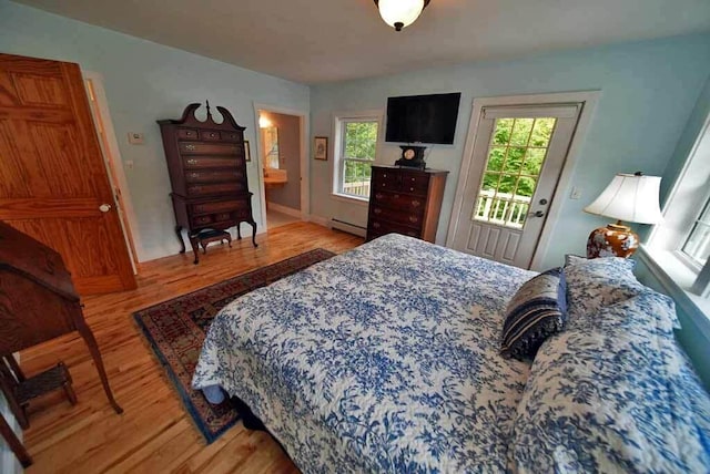 bedroom with a baseboard heating unit, access to outside, and light wood-type flooring