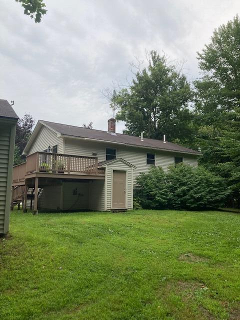 back of house with a lawn, a chimney, and a deck