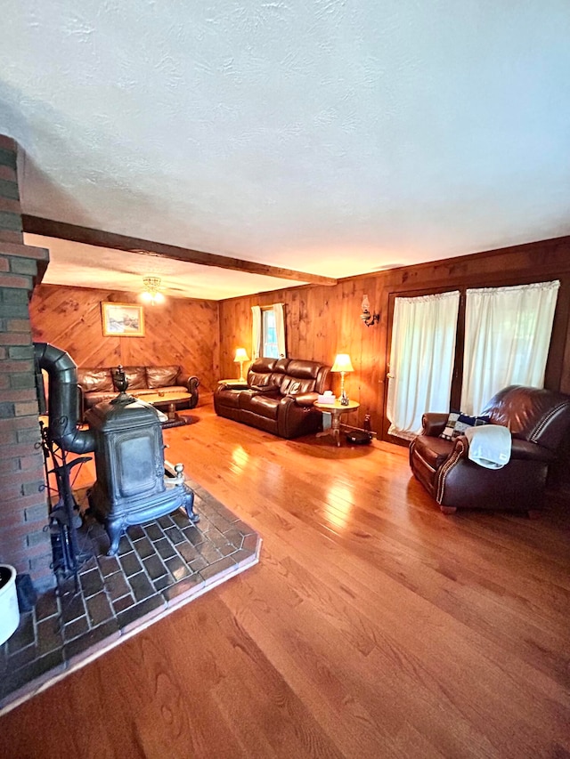 living room with a textured ceiling, wood-type flooring, beam ceiling, and wooden walls