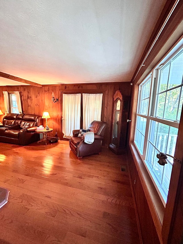 unfurnished living room with a textured ceiling, wood walls, and wood-type flooring