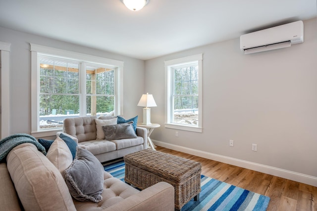 living room with wood finished floors, baseboards, and a wall mounted AC