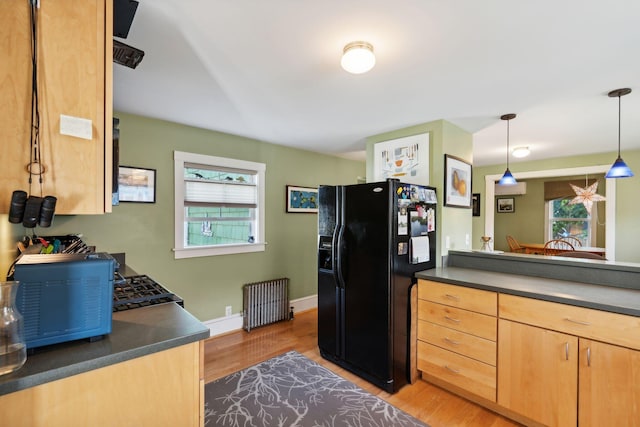 kitchen featuring decorative light fixtures, light brown cabinets, black fridge with ice dispenser, radiator heating unit, and light wood-type flooring