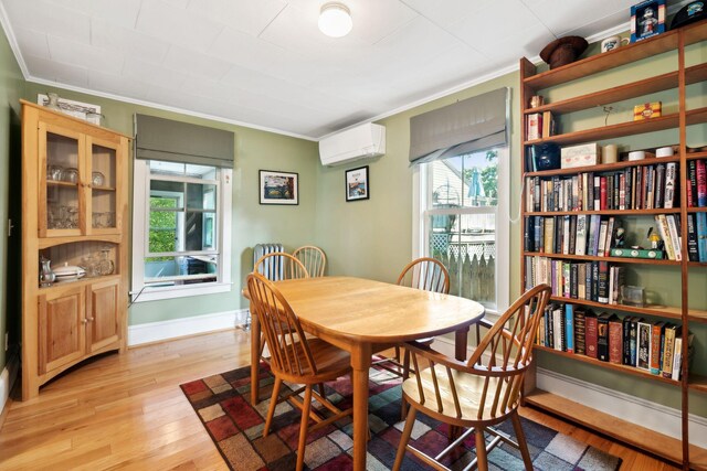 dining room featuring crown molding, an AC wall unit, and light hardwood / wood-style flooring