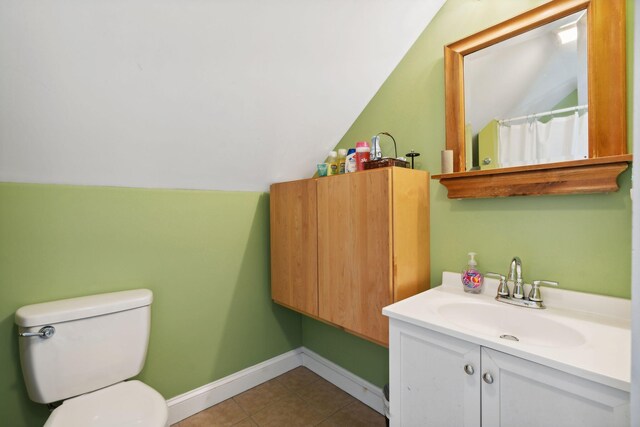 bathroom with vanity, toilet, vaulted ceiling, and tile patterned flooring