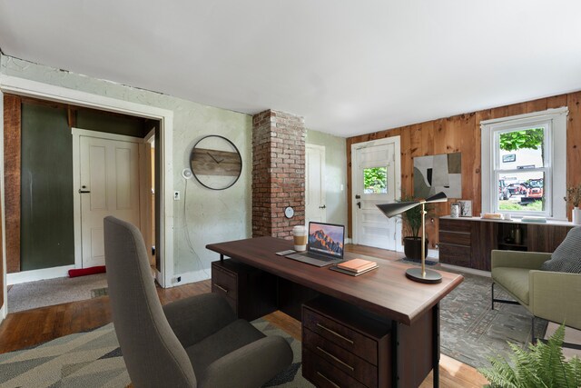 home office featuring brick wall, wooden walls, and wood-type flooring